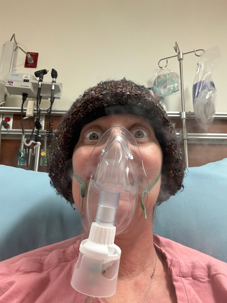 Danell making a silly face with an oxygen mask on in her hospital bed
